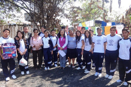 Grupo de estudiantes del primer año de bachillerato en la UE San José, posa junto a una profesora, un padre de familia y la persona beneficiaria de la ayuda humanitaria que llevaron. Manta, Ecuador.
