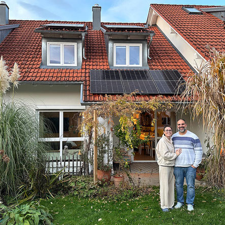Zufriedene Kunden vor Einfamilienhaus mit PV-Analge auf dem Dach