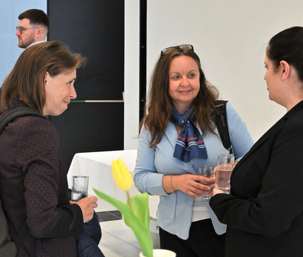Drei Frauen tauschen sich bei Getränken freundlich aus.