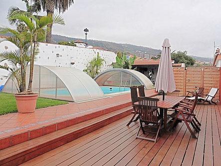 Überdachter Pool mit Rasenfläche und Holzterrasse .