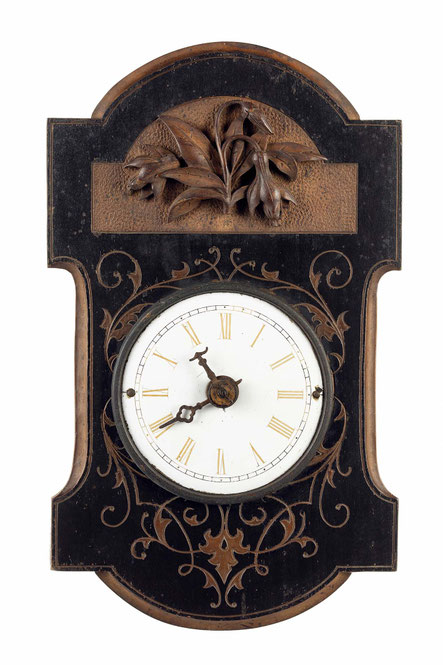 sehr kleine schwarzwälder Uhr mit einem geschwärztem Holzschild. In die Holzoberfläche sind Ornamente eingraviert und im oberen Bereich ein geschnitztes Blumenornament aufgesetzt. Die Form des Schildes hat eine freie Form und vermutlich aus Birnbaumholz.