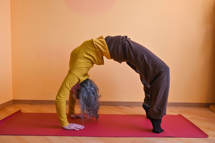 Das Rad (cakrāsana) zeigt eine lang ausgedehnte und nach vorne in Richtung Brustkorb geschobene Brustwirbelsäule.