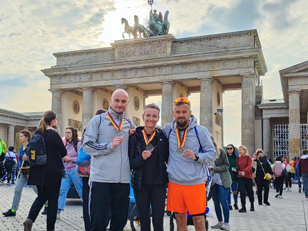 Dirk Gutsche, Frauke Neumann und Thorsten Jockisch mit Medaillen vor dem Brandenburger Tor.