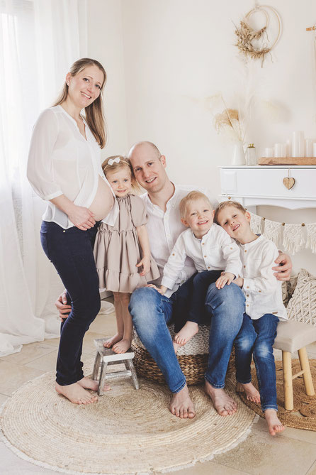 Schwangere Frau mit Mann und drei kleinen Kindern. Babybauch-Fotografie 