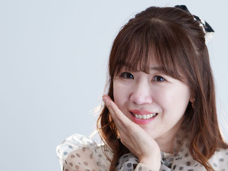 手を頬に添えて微笑むきょんちゃん。ドット柄のチュールブラウス姿が愛らしいポートレート。