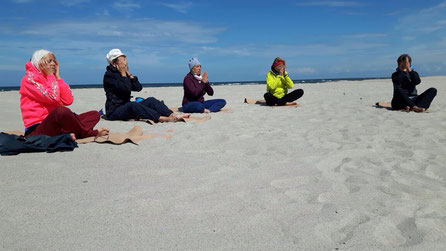 Zum Beginn der Yogastunde am Strand sanft das Gesicht ausstreichen.