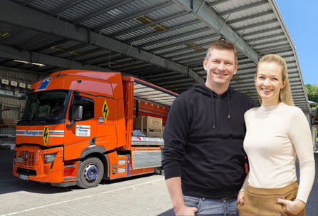 Die Werkstatt-Crew hat sich vor dem Truck aufgestellt. Etwa 18 Mitarbeiter haben blaue und zum Teil schwarze Kleidung an.