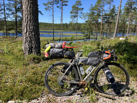 Bikepacking in Mittelschweden mit voll bepacktem Gravelbike an einem einsamen Waldsee bei Gyttorp, umgeben von Kiefern und skandinavischer Natur.