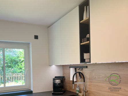 Kompakte U-Küche vom Schreiner mit deckenhohen weißen Hängeschränken, offenem Regal in Anthrazit mit Holzböden, Holzdekor-Nischenrückwand, LED-Arbeitslicht, großem schwarzen Spülbecken mit mobilem Abtropfblech, Relingsystem mit Papierrollenhalter 
