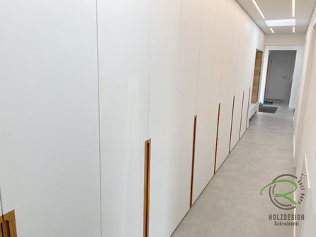 8,50 m langer raumhoher Einbauschrank in weiß & Eiche-Griffleisten mit offener Garderobennische von Schreinerei Holzdesign Ralf Rapp in Geisingen