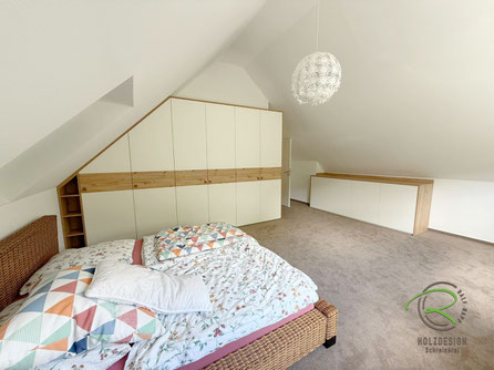 Maßgefertigter Schlafzimmereinbauschrank mit Schräge links, offenem Regal mit Schräge und Dachnischenschrank von Schreinerei Holzdesign Ralf Rapp in Geisingen in weiß und Eiche Holzdekor mit eleganten Ledergriffen