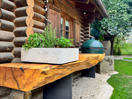 Big Green Egg integriert in massive Baumstammbohlen aus Geisinger Esche mit naturgeschwungener Baumkante im Außenbereich