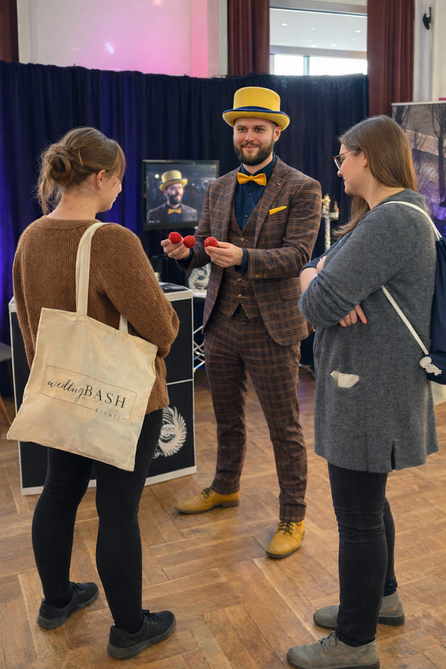 Magier Johannes zaubert auf einer Messe für zwei Zuschauer, Messebesucher