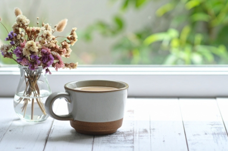 オフィスの窓辺に飾られたドライフラワーとコーヒーの入ったマグカップ。