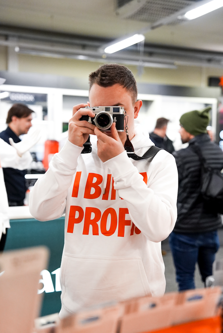 Person hält eine Kamera ans Auge und testet sie während der Fotomesse, bei der Workshops und Produkttests angeboten werden.