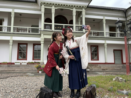 桐生明治館の前で自撮りをする卒業式の女学生（AI編集）
