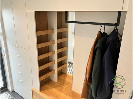 Maßgefertigter Garderobenschrank in Radolfzell von Schreinerei Holzdesign Ralf Rapp in Geisingen in weiß und schwebender Eichen-Sitzbank mit offenem, verstecktem Regal für Accessoires, schwarzer Garderobenstange in U-Form u. flächenbündigem Spiegel