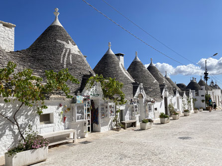 trulli di Alberobello con tetto in pietra grigia a punta e base bianca in pietra, uno in fila all'altro