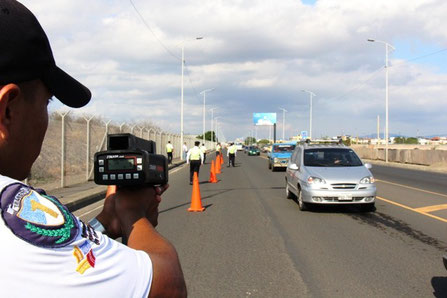 Un agente de tránsito controla el límite de velocidad con el uso de un radar portátil. Manta, Ecuador.