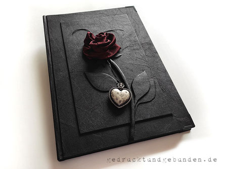 Kondolenzbuch, Hardcover-Bucheinband, Stoffeinband schwarz, erhabenes Relief Stiel und Blätter der Rose, Rose handgenäht, dunkelroter Crashtaft, Herzanhänger altsilberfarben, Buchecken schwarz, A4 Hochformat.