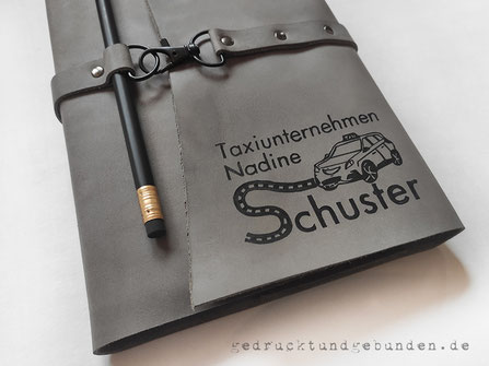 Lederumschlag für Jahreskalender A5, Verschluss Lederriemen genietet, Überschlag mit Beschriftung und Logo.