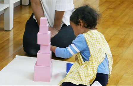 幼児教室のモンテッソーリ活動で、2歳児が感覚教具のピンクタワーを使った活動を行い、順序づけ の感覚を育んでいます。