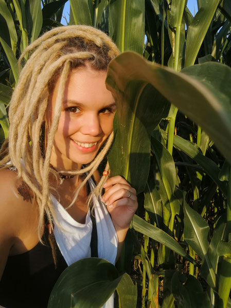 Meditationslehrerin und Happiness Trainerin Sabrina Sierks lächelt vor einem Maisfeld in die Kamera.