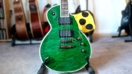 Grüne E-Gitarre in Les Paul-Bauweise, über deren Korpus eine Blindenarmbinde hängt