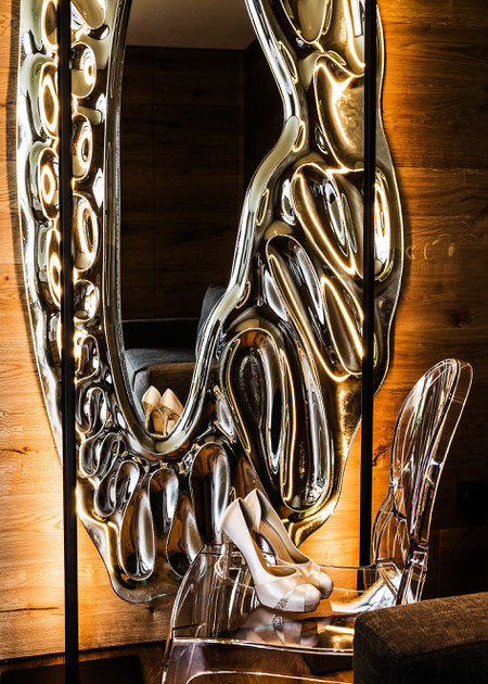 Kontraste zum warmen Holz bilden Accessoires mit kühlem Charakter wie dieser Wandspielgel und der Stuhl " Ghost" von Kartell