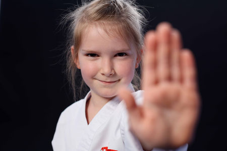 Mädchen auf dem Bild. Das Mädchen macht das Stop zeichen mit der Hand. Sicherheitsteil im Karate. Selbstschutz und Selbstverteidigung.