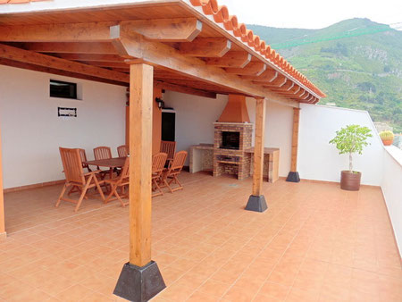 Große geflieste Terrasse mit Gartenmöbel und Grill, sowie Blick auf das Meer.