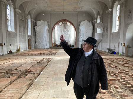 Pfarrer Bernhard Friedmann erklärt in der leer geräumten Kirche St. Vitus, was alles saniert wird. Foto: Benjamin Kemmer