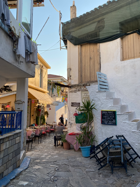 una stradina del centro di Skiathos con ristorante tipico con tovaglie a quadri rossi, panni stesi alle finestre
