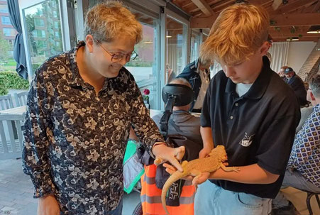 Onze vrijwilligers op een evenement met een dierenpresentatie, samen met een jongen op de foto die een koningspython om zijn nek heeft