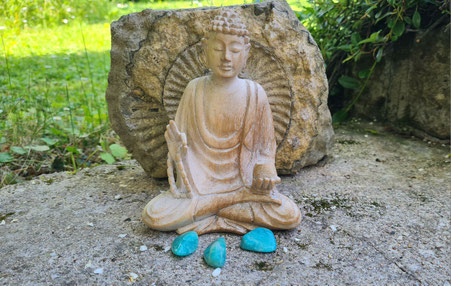 Nahaufnahme eines Buddas auf Moos sitzend mit dem Stein des Monats vor sich liegend. Steht symbolisch für Svenja Lampkes Stein des Monats.