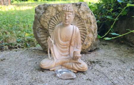 Nahaufnahme eines Buddas auf Moos sitzend mit dem Stein des Monats vor sich liegend. Steht symbolisch für Svenja Lampkes Stein des Monats.