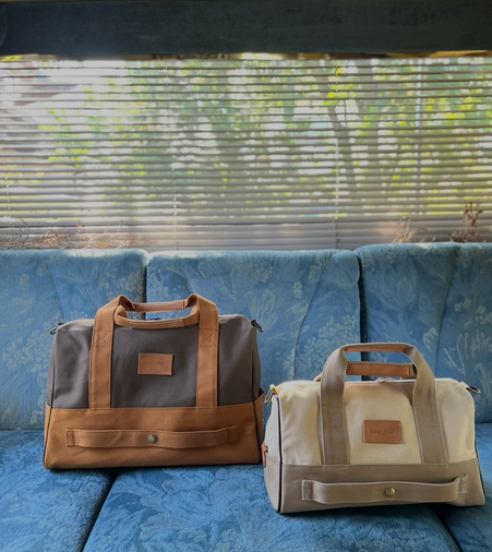 帆布のボストンバッグCarry-On。向かって右側の帆布バッグはアイボリーとベージュの組み合わせのバッグで、それより一回り大きめのサイズが向かって右側のバッグで、茶色とキャメルのカラーバッグです