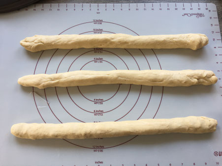 Teig auf Backmatte in drei Strängen geteilt