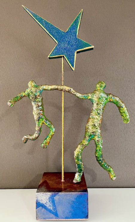 Skulptur ELEVARE von Andreas Alka alias FLoYd – zwei farbintensive Figuren aus lackgetränktem Baustahl Bindedraht, die an einer zentralen Stahlachse mit blauem Holzstern emporragen. Symbol für Vertrauen, Zuversicht und unsichtbare Kraftquellen.