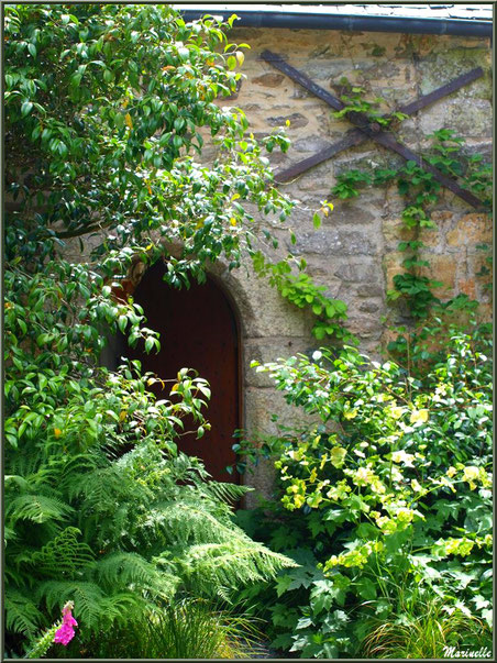 Le Manoir : un bâtiment annexe à l'entrée avec une ses portes dans un écrin de végétation - Les Jardins du Kerdalo à Trédarzec, Côtes d'Armor (22)