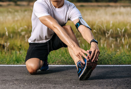Photo d'un sportif qui s'étire la cheville gauche après sa course à pied