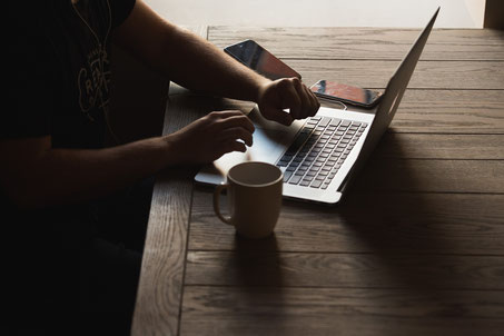 Person an Laptop mit Kaffee