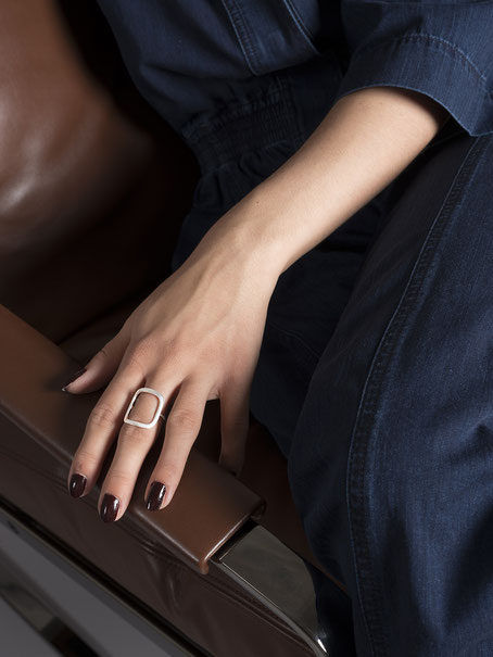 main de femme accoudée à un siège en cuir brun portant une bague Q01 en argent recyclé de la collection Quadra