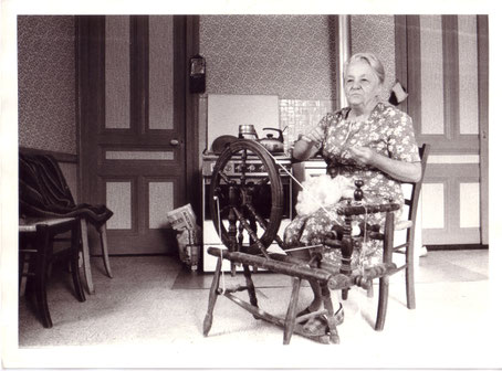 Madame Raquin, dit "Doddie" filant au rouet dans sa cuisine (Archives familiales)