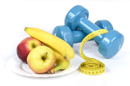 Gewichte für den Sport und Banane und Apfel für eine gesunde Ernährung