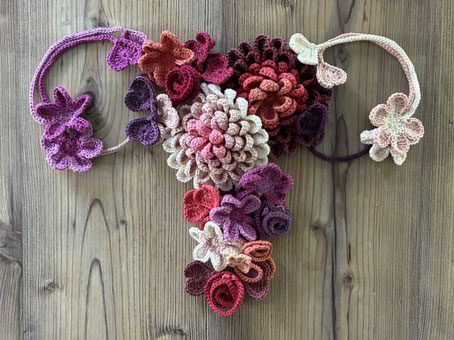eine Gebärmutter wurde aus diversem Arbeitsmaterial für die Geburts- und Stillberatung (Muttermund-Blumen, Nabelschnurbändchen) wie eine Collage zusammengesetzt  