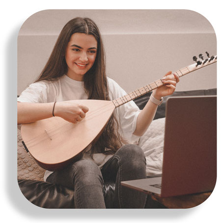 Schülerin der Musikschule Hückelhoven sitzt gemütlich auf dem Sofa mit ihrer Saz in den Händen und nimmt mit ihrem mobilen Gerät am online Saz bzw. Baglama Unterricht teil.