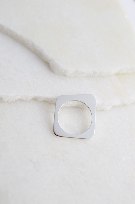 bague géométrique Forma F02 en argent brillant posée sur du marbre