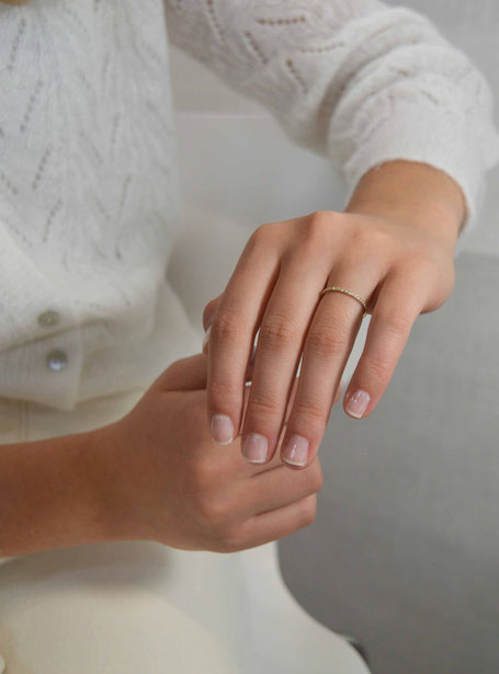 main de femme portant une fine bague en or jaune entièrement sertie de diamants