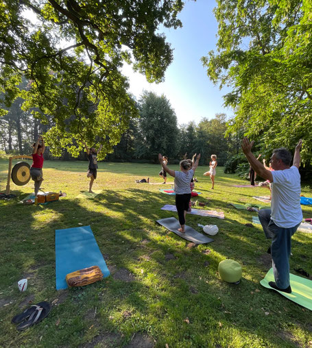 eien Gruppe von Menschen macht Yoga im Großen Garten Dresden auf der Weise zwischen Bäumen 